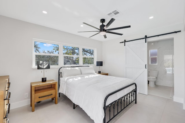 bedroom with ceiling fan, connected bathroom, and a barn door