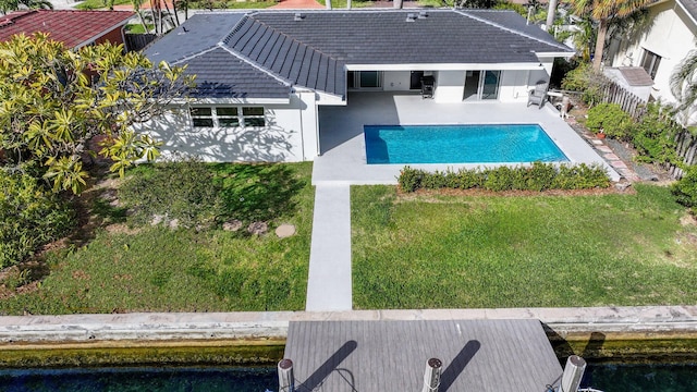 view of pool featuring a boat dock, a patio, and a lawn