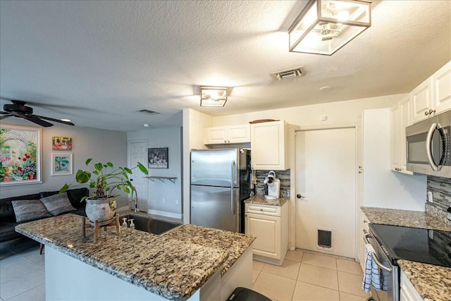 kitchen with light tile patterned flooring, appliances with stainless steel finishes, sink, and white cabinets