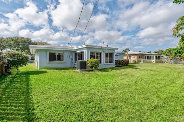 back of property featuring central AC unit and a lawn