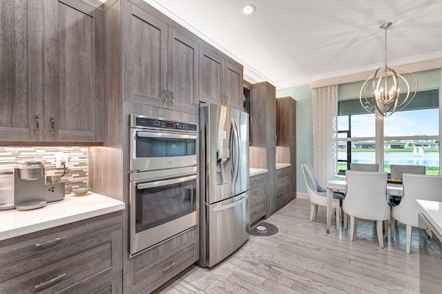 kitchen with a water view, an inviting chandelier, hanging light fixtures, light wood-type flooring, and appliances with stainless steel finishes