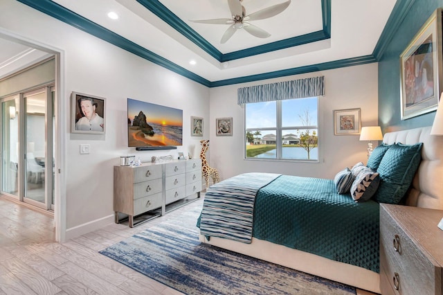 bedroom featuring ornamental molding, light wood-type flooring, ceiling fan, and a tray ceiling