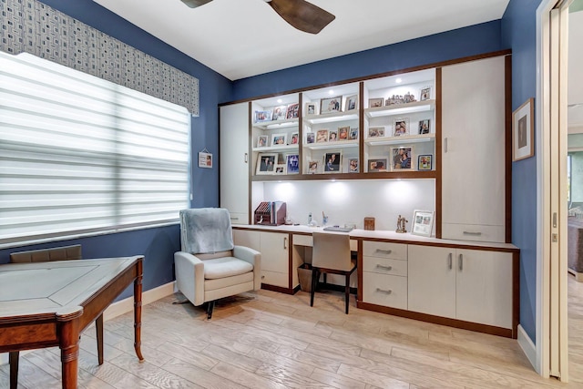 office space with light wood-type flooring, built in study area, and a ceiling fan