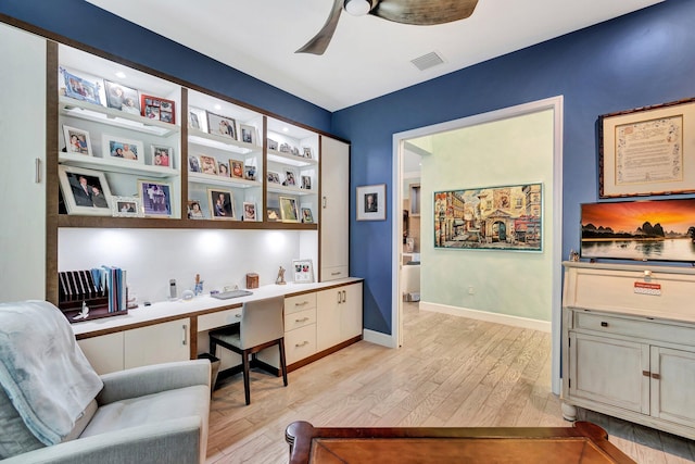 office area featuring built in desk, ceiling fan, and light wood-type flooring