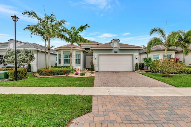 mediterranean / spanish-style house featuring a front yard, a garage, decorative driveway, and stucco siding