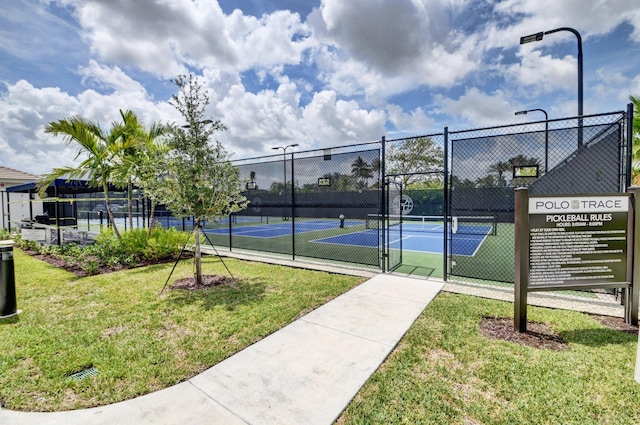 view of tennis court with a yard, fence, and a gate