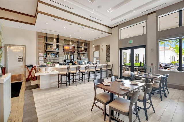 dining area with french doors, a towering ceiling, and light hardwood / wood-style floors