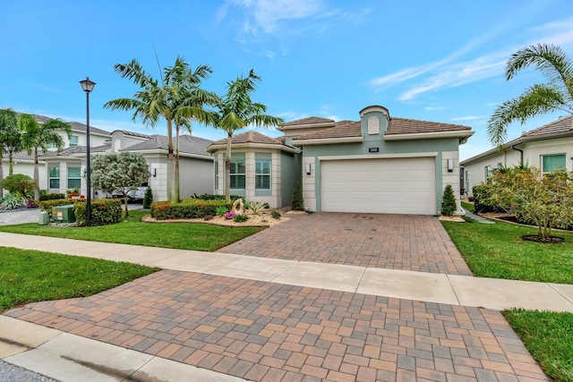 mediterranean / spanish house with an attached garage, stucco siding, decorative driveway, and a front lawn