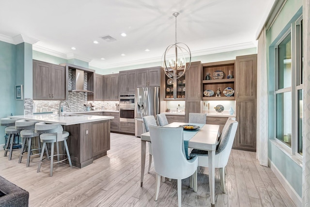 dining room featuring crown molding, a chandelier, sink, and light hardwood / wood-style flooring