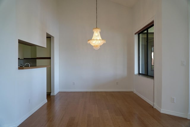 unfurnished dining area featuring sink, an inviting chandelier, and wood-type flooring