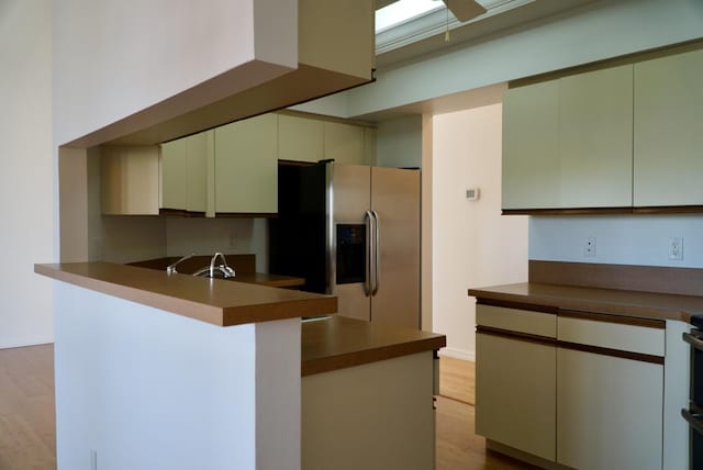 kitchen featuring stainless steel refrigerator with ice dispenser, light hardwood / wood-style floors, sink, and kitchen peninsula