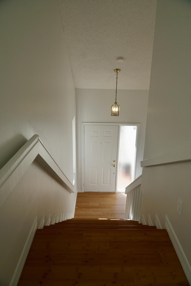 stairs featuring hardwood / wood-style flooring and a textured ceiling