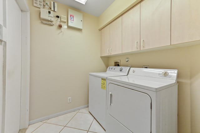 laundry room featuring light tile patterned flooring, cabinets, a skylight, and washer and dryer