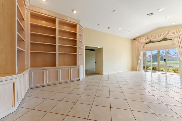 unfurnished living room with built in shelves, vaulted ceiling, and light tile patterned floors