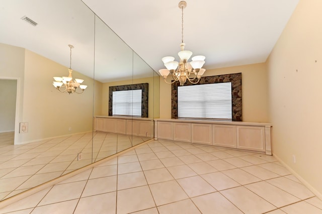 spare room with an inviting chandelier, lofted ceiling, and light tile patterned floors