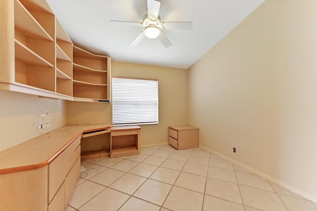 unfurnished office featuring ceiling fan, built in desk, and light tile patterned floors