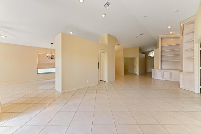 unfurnished room featuring lofted ceiling, light tile patterned floors, a chandelier, and built in shelves