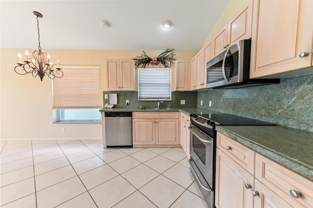 kitchen featuring sink, hanging light fixtures, light tile patterned floors, appliances with stainless steel finishes, and decorative backsplash