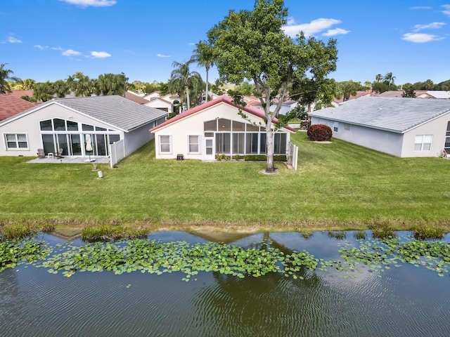 rear view of house featuring a water view, a yard, and a sunroom