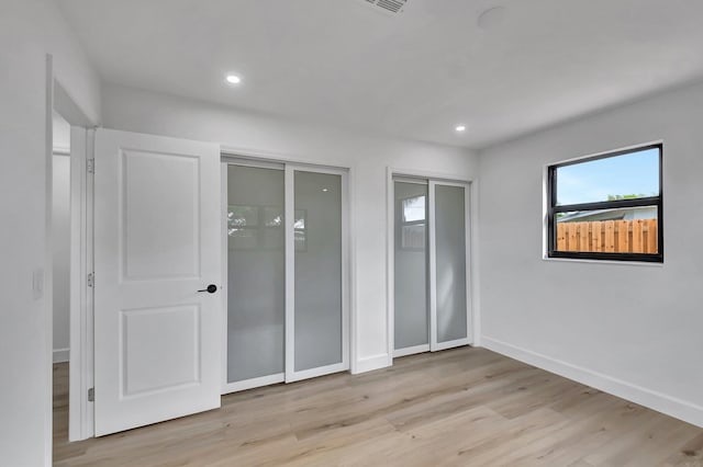 unfurnished bedroom with two closets and light wood-type flooring