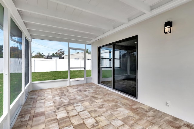 unfurnished sunroom featuring beam ceiling