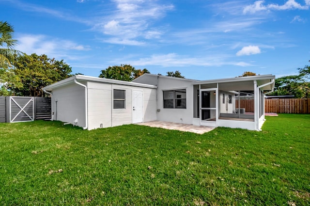 back of house with a sunroom, a patio area, and a lawn