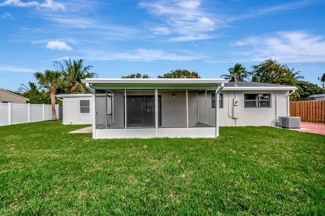 back of property with a sunroom, a yard, and central AC unit