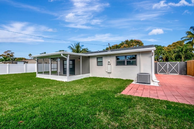 rear view of house with a sunroom, central air condition unit, and a lawn