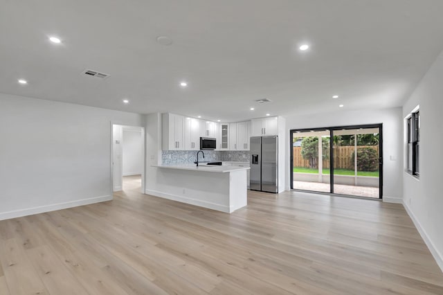 kitchen with sink, white cabinetry, light hardwood / wood-style flooring, appliances with stainless steel finishes, and kitchen peninsula