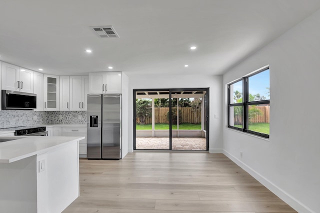 kitchen featuring white cabinetry, backsplash, light wood-type flooring, and stainless steel refrigerator with ice dispenser