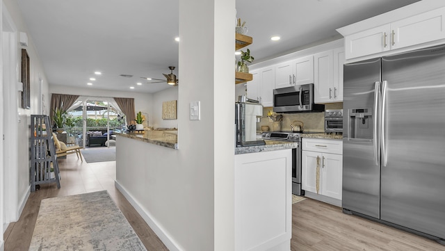 kitchen featuring white cabinets, appliances with stainless steel finishes, light wood-type flooring, and tasteful backsplash