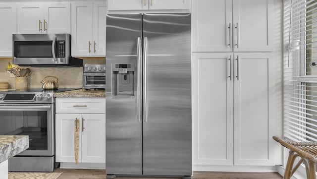 kitchen featuring light stone counters, white cabinets, and stainless steel appliances