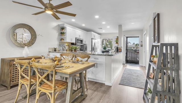 kitchen with light hardwood / wood-style floors, light stone countertops, appliances with stainless steel finishes, white cabinets, and kitchen peninsula