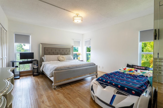 bedroom with a closet, wood-type flooring, and a textured ceiling