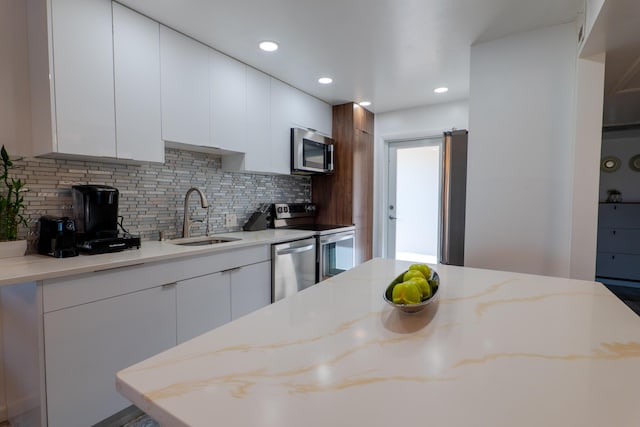 kitchen with stainless steel appliances, sink, white cabinets, and decorative backsplash