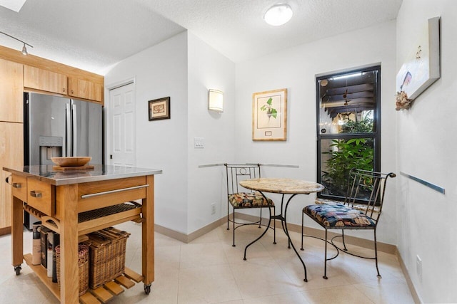 dining space with a textured ceiling, light tile patterned flooring, and baseboards