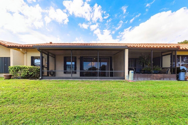 rear view of house featuring a yard, a tile roof, and a sunroom