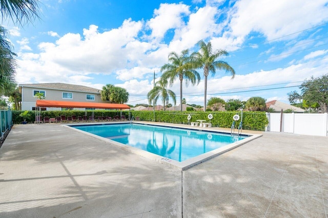 pool with a patio area and fence