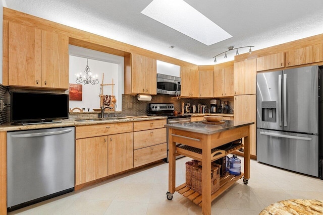 kitchen with a skylight, stainless steel appliances, tasteful backsplash, light brown cabinetry, and a sink