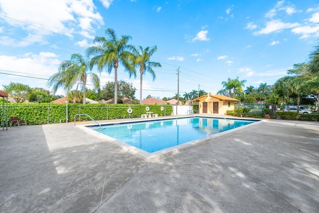 pool with a patio, an outdoor structure, and fence