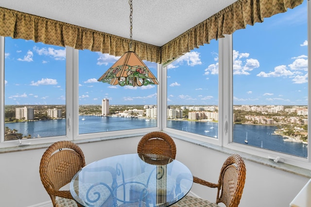 dining space with a water view and a textured ceiling