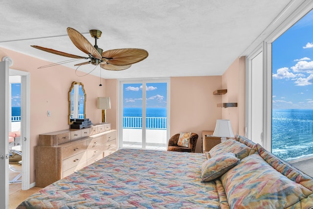 bedroom with floor to ceiling windows, a water view, a ceiling fan, and access to exterior