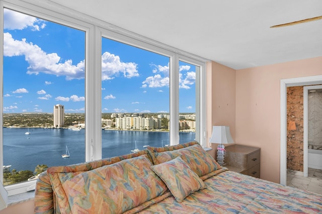 bedroom featuring access to exterior, marble finish floor, a water view, and ensuite bath