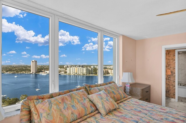 bedroom with a view of the beach, a wall of windows, ceiling fan, access to exterior, and a water view