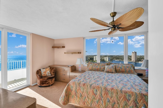 carpeted bedroom with access to outside, a wall of windows, and a water view