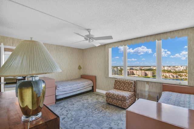 bedroom with a view of city, a ceiling fan, and a textured ceiling