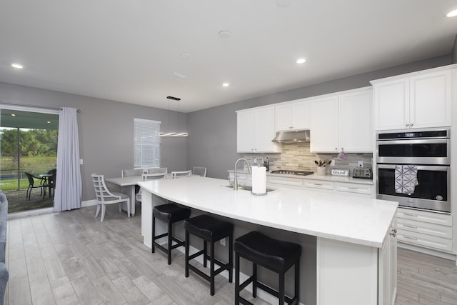 kitchen featuring appliances with stainless steel finishes, a center island with sink, and white cabinets