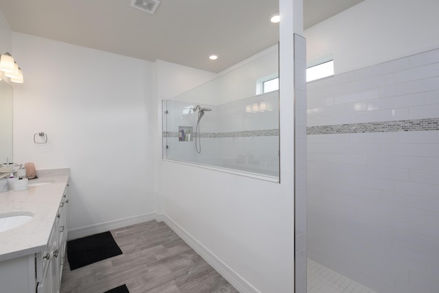 bathroom featuring vanity, hardwood / wood-style floors, and a tile shower