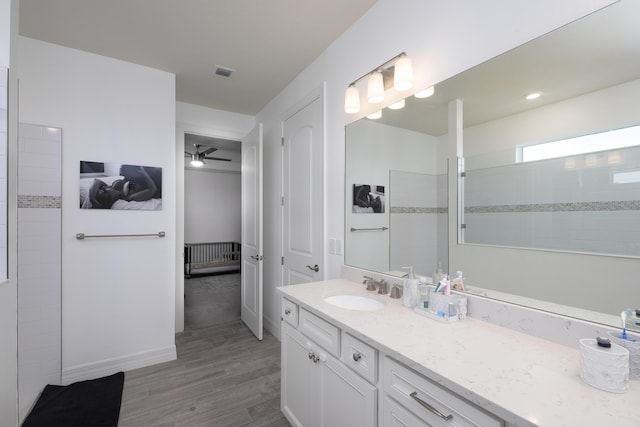 bathroom with ceiling fan, vanity, wood-type flooring, and a tile shower