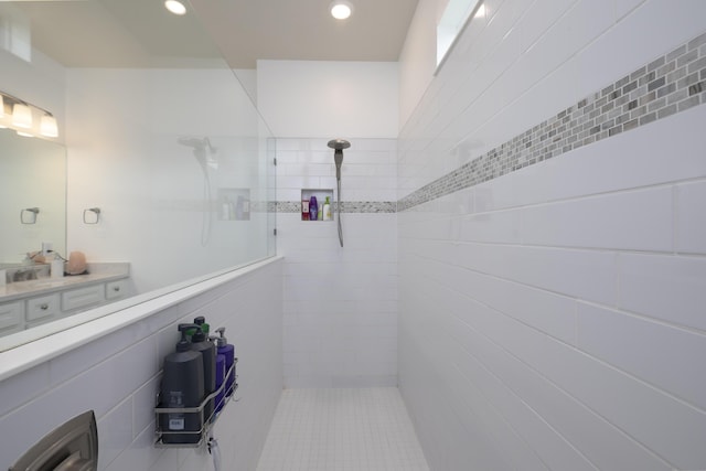 bathroom with a tile shower and tile walls